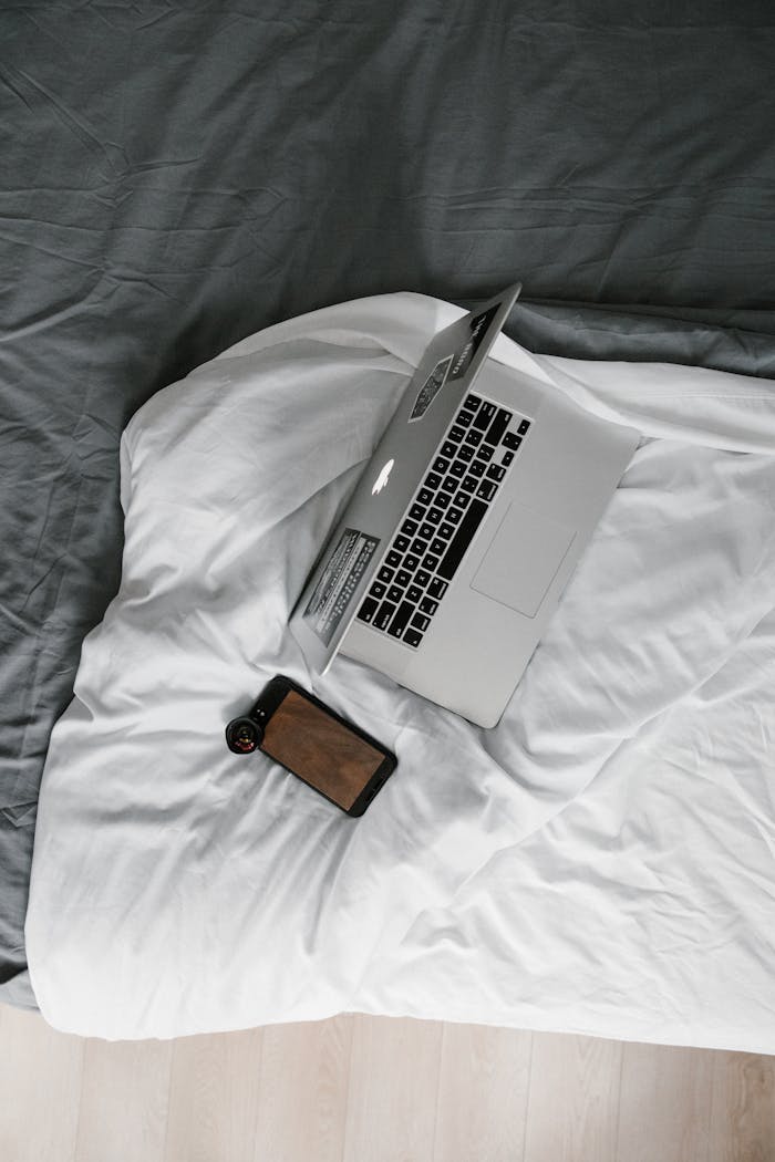 Home Minimalist overhead view of a laptop and smartphone on a cozy bed, ideal for remote work settings.